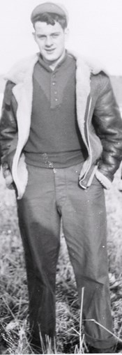 A man stands in a field wearing a bomber jacket A man stands in a field wearing a bomber jacket