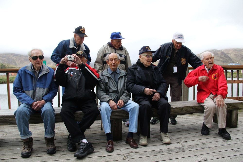 Eight men pose for a photo on a porch