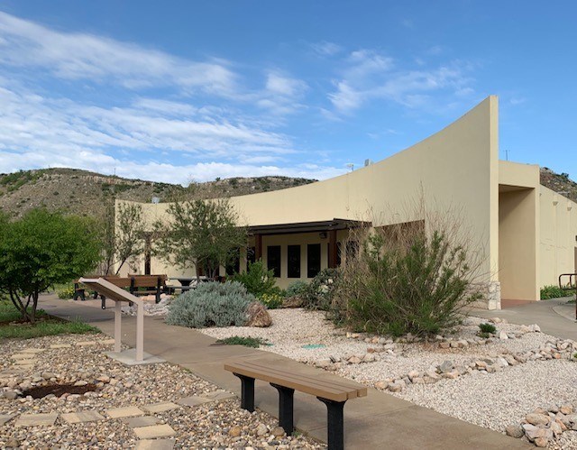 Alibates Visitor Center with xeriscaping rock garden and desert willow trees.  It is a sunny day with blue skies.