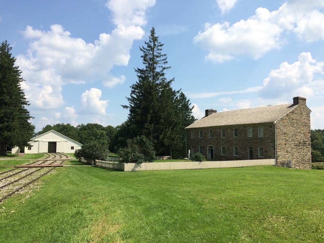 An engine house building and a stone tavern along the railroad.