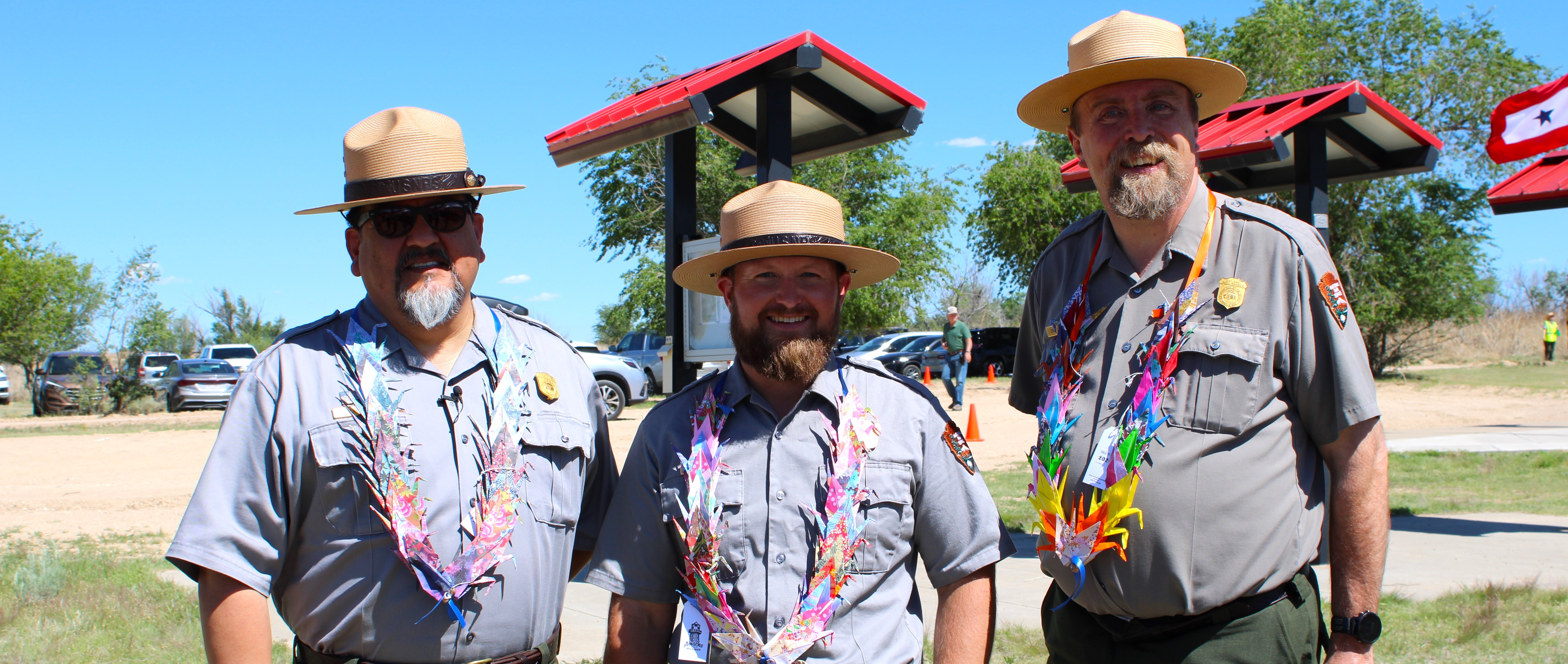 Three male park rangers standing in a row smiling