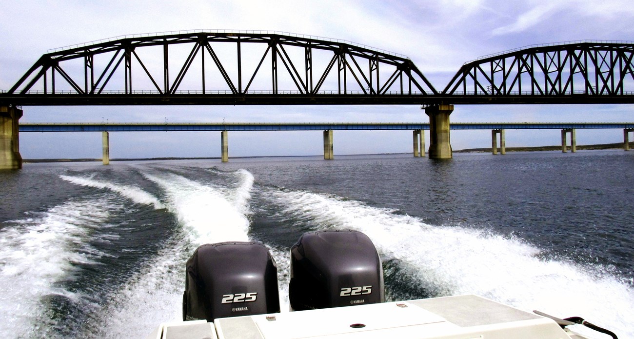 A motorboat's wake as it moves away from the bridge