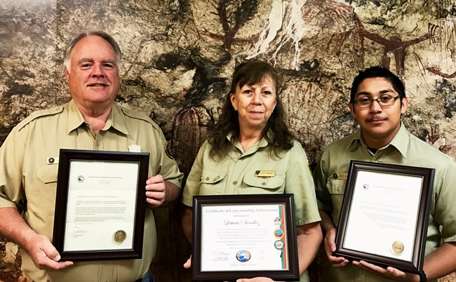 Three volunteers, 2 men and a woman, shown with their awards from 2016-2017