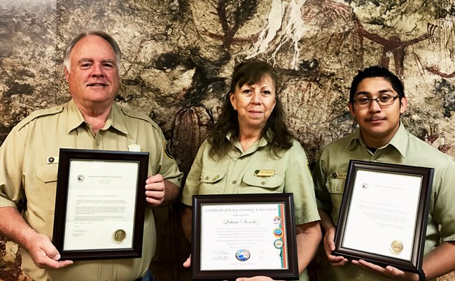 Three volunteers, 2 men and a woman, shown with their awards from 2016-2017
