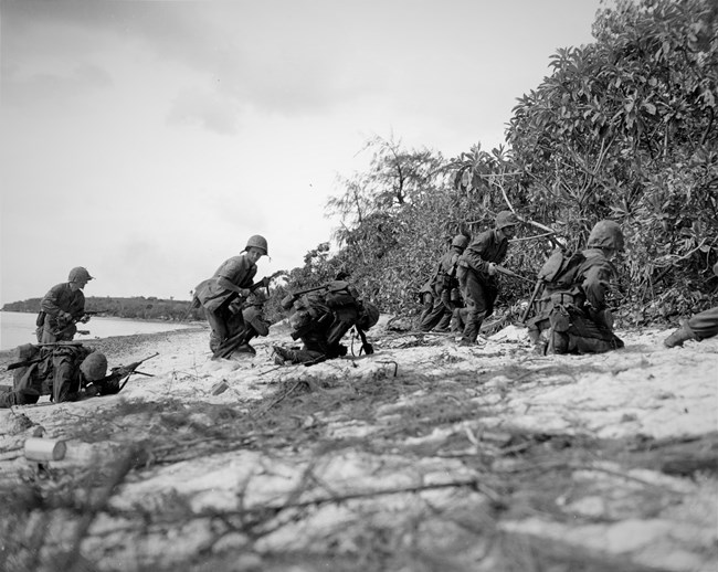 Saipan Operation, June-July 1944 Japanese Snipers hit two Marines (center and left) as a landing party storms ashore during the final stages of the conquest of Saipan. Taken by a U.S. Coast Guard Photographer.
