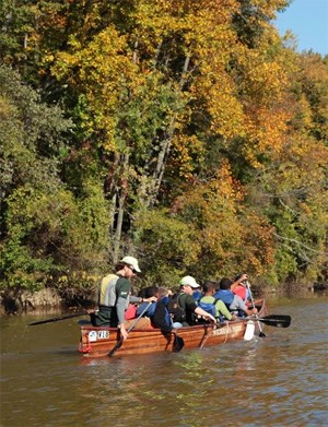 A group of people paddle a large canoe. A group of people paddle a large canoe.