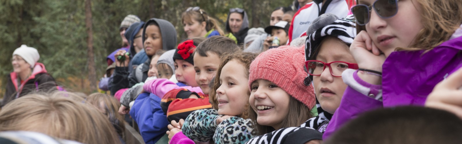 Students standing on bleachers watching an unknown subject.
