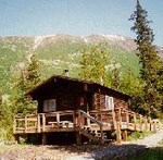Log cabin in outdoor setting with mountain in background.