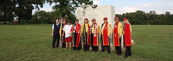 Men in ceremonial dress standing before a stone monument