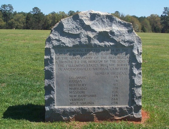 A stone monument with text octaed in a grassy field.