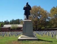 Stone and Bronze monument of a Civil War soldier surrounded by white headstones Stone and Bronze monument of a Civil War soldier surrounded by white headstones