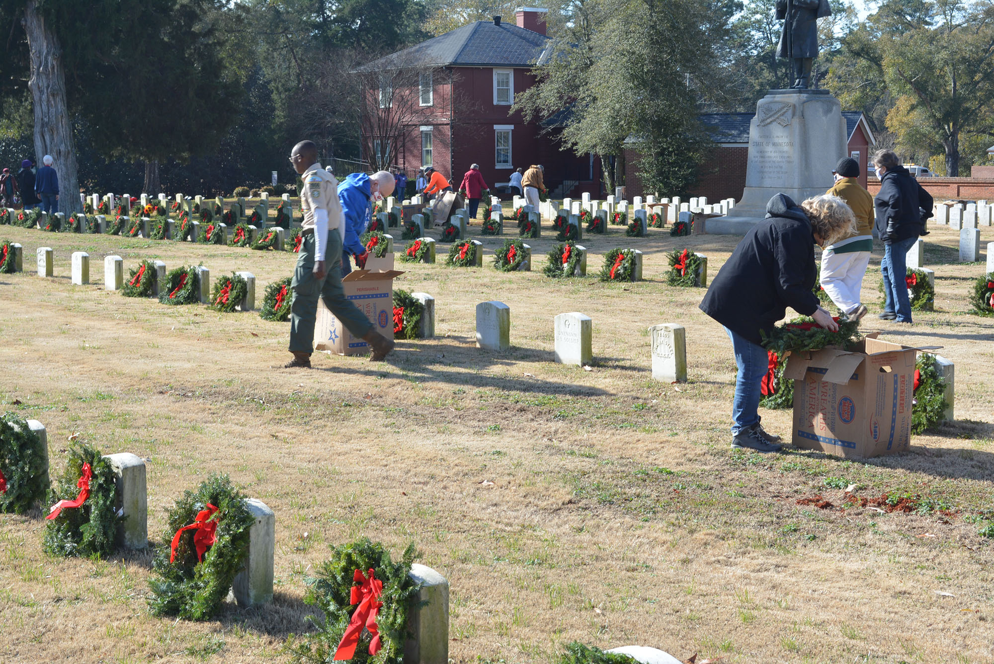 Volunteers placing wreaths on headstones