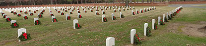 Pine wreaths decorate rows of headstones.