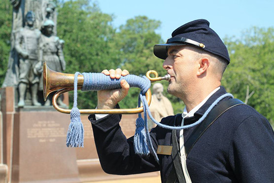 A volunteer in Union uniform blows Taps