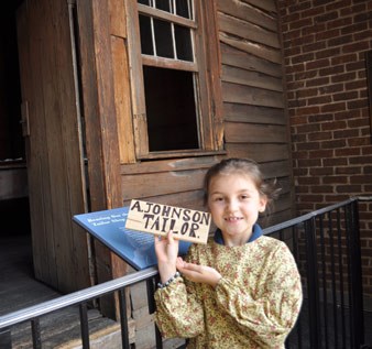 Visitor with try-on clothes holding a tailor shop shingle