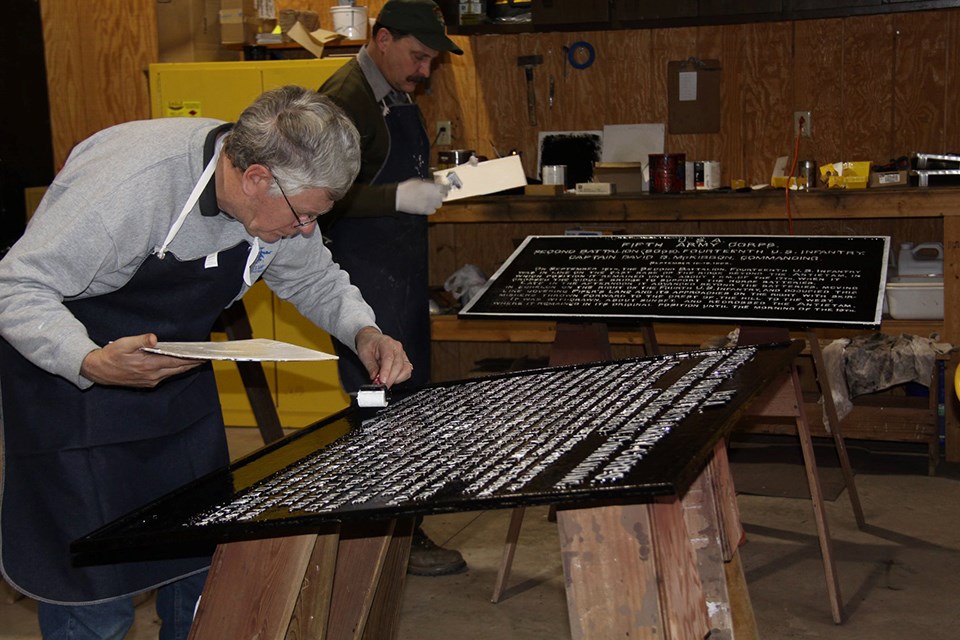 Volunteer paints one of the War Department tablets.