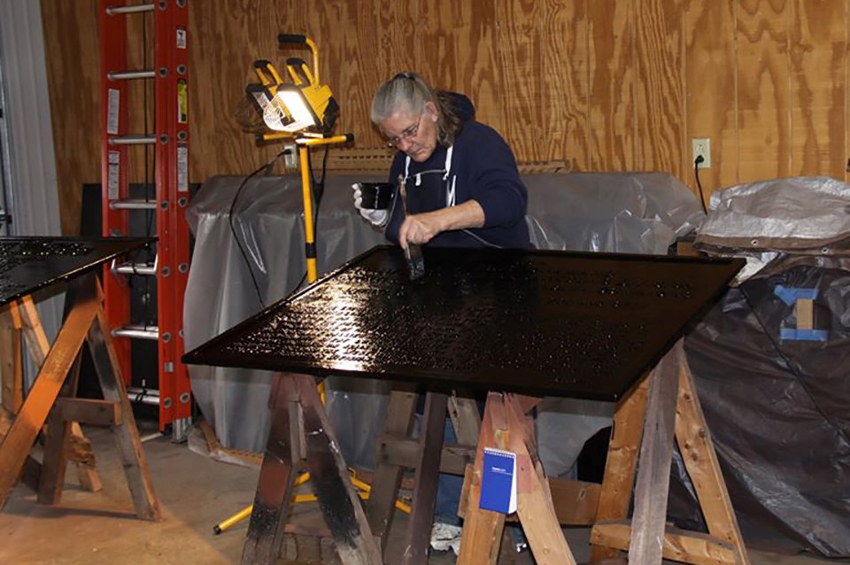 Volunteer paints the black background of one of the War Department tablets.