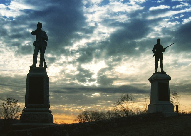 two soldier monuments at sunrise