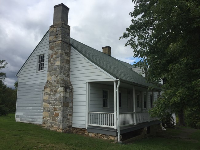 side of a white house with a stone chimney