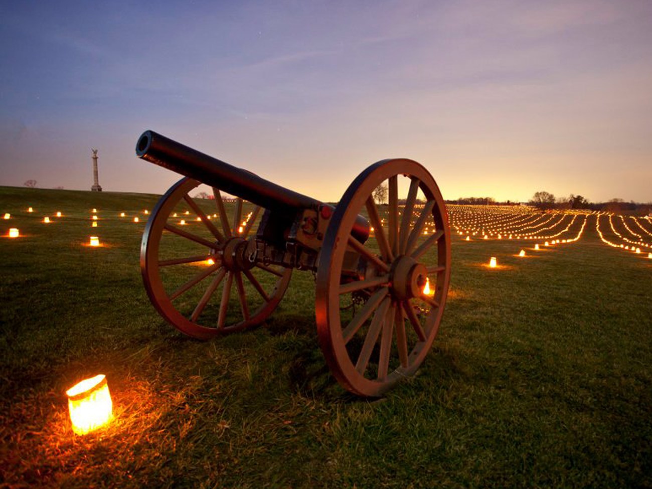 Image of a Civil War cannon and thousands of luminaries