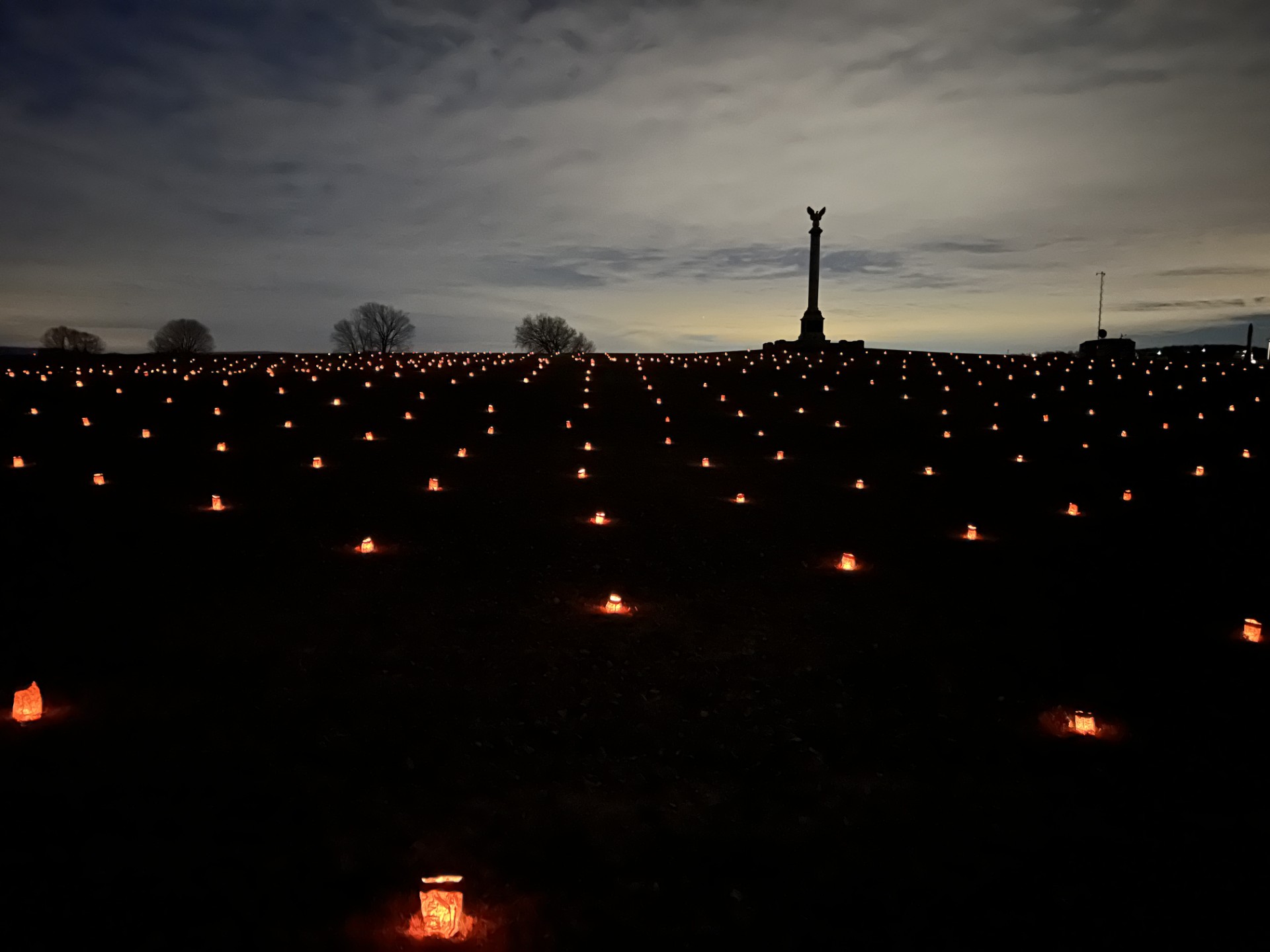 rows of luminaries at night with monument in background