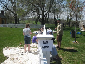 Volunteers painting white picket fences in the village.