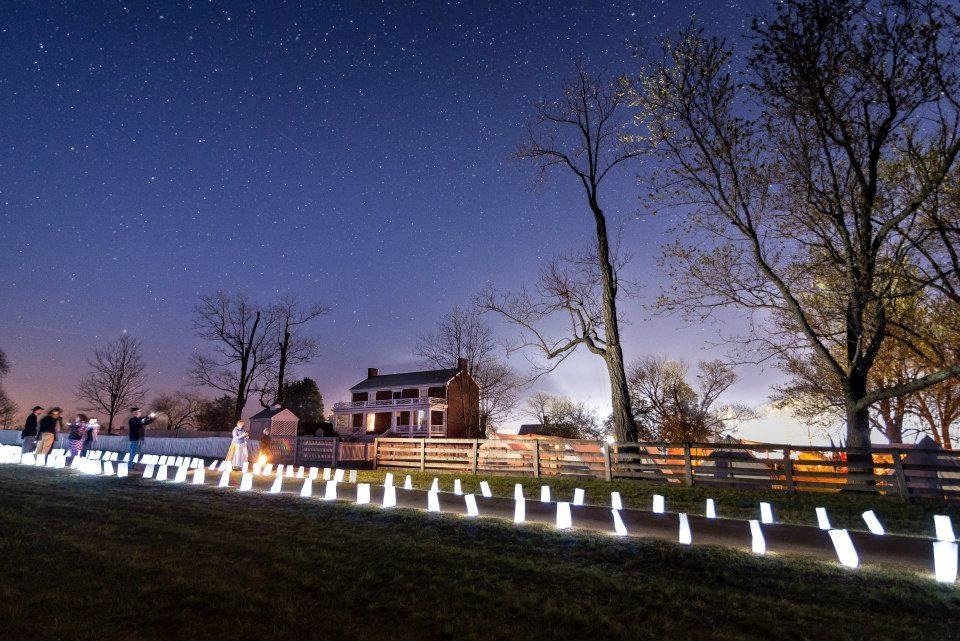 Surrender Anniversary Luminary white luminaries light up the brick McLean house and add glow to the dirt road under a deep blue sky