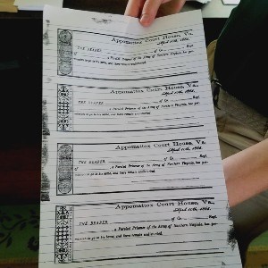 Two hands hold a piece of white, lined paper with four bank-check sized slips printed in black ink. Each section is an individual parole pass.
