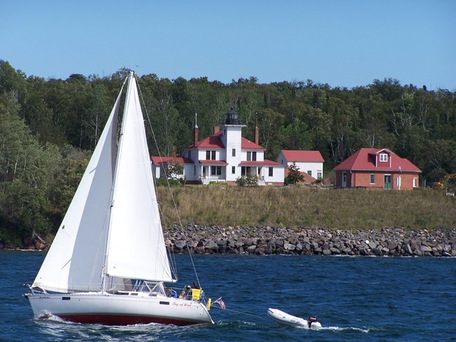 Photograph of sailboat passing in front of Raspberry Island Lighthouse.