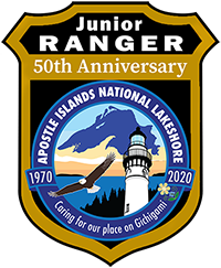 A badge showing Lake Superior, an eagle, lighthouse and trees.