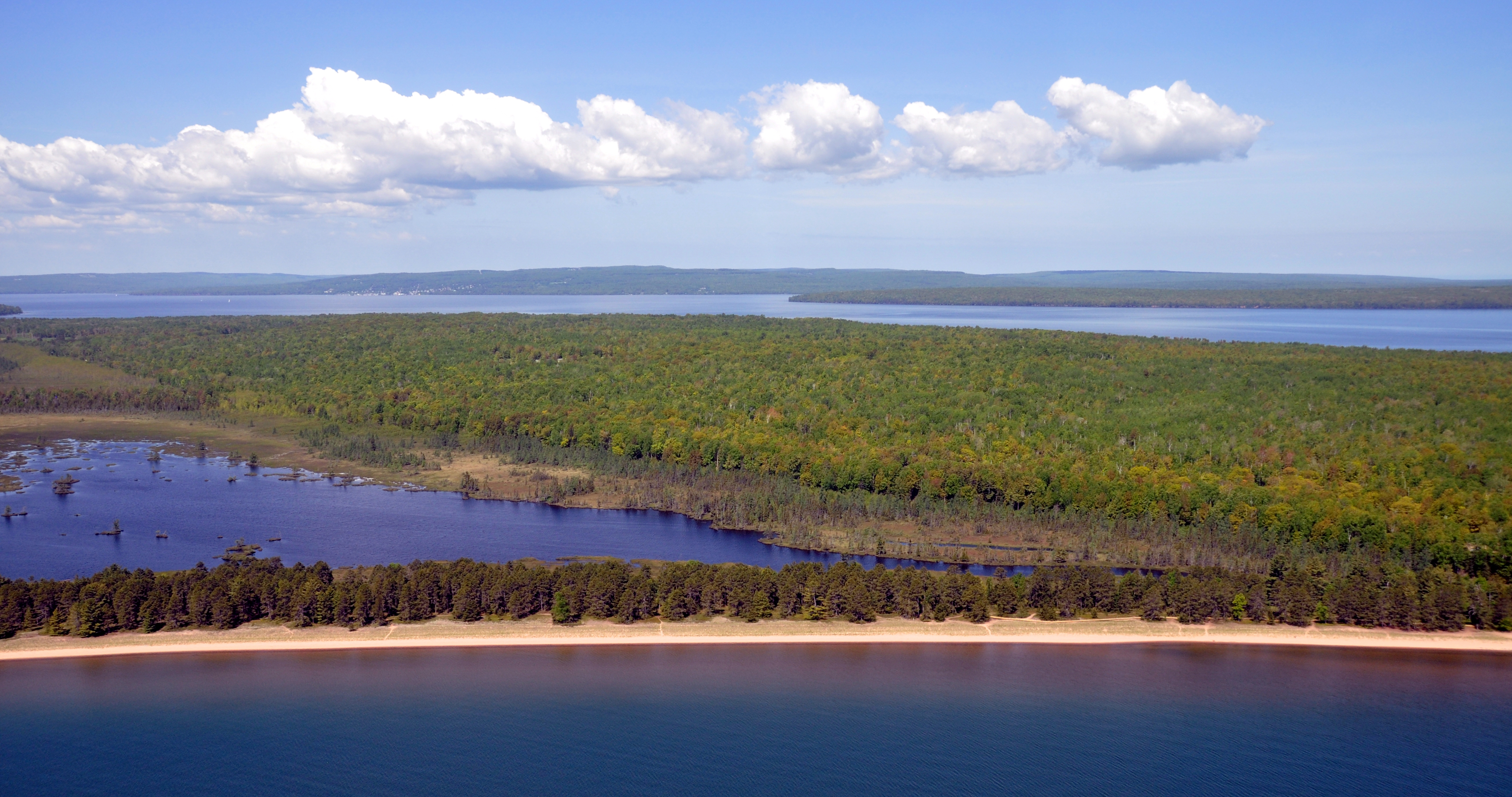 Aerial view of an island lagoon with other islands in the distance and a blue sky with clouds above.