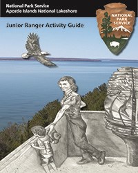 Cover of the Junior Ranger Book, showing blue water, lighthouse, a penciled in ranger and child.