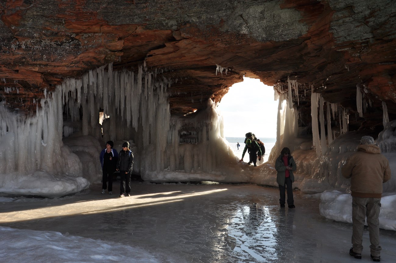 Visitors inside and climbing into an ice cave.