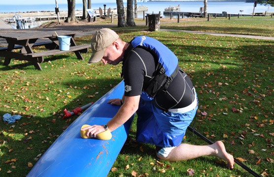 Kayaker cleaning his boat of invasives