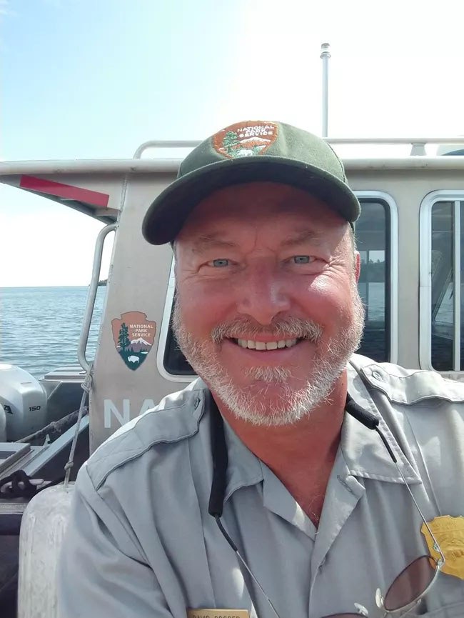 On a National Park Service boat a man smiles at the viewer.