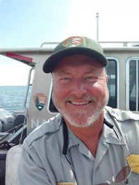 On a National Park Service boat a man smiles at the viewer.
