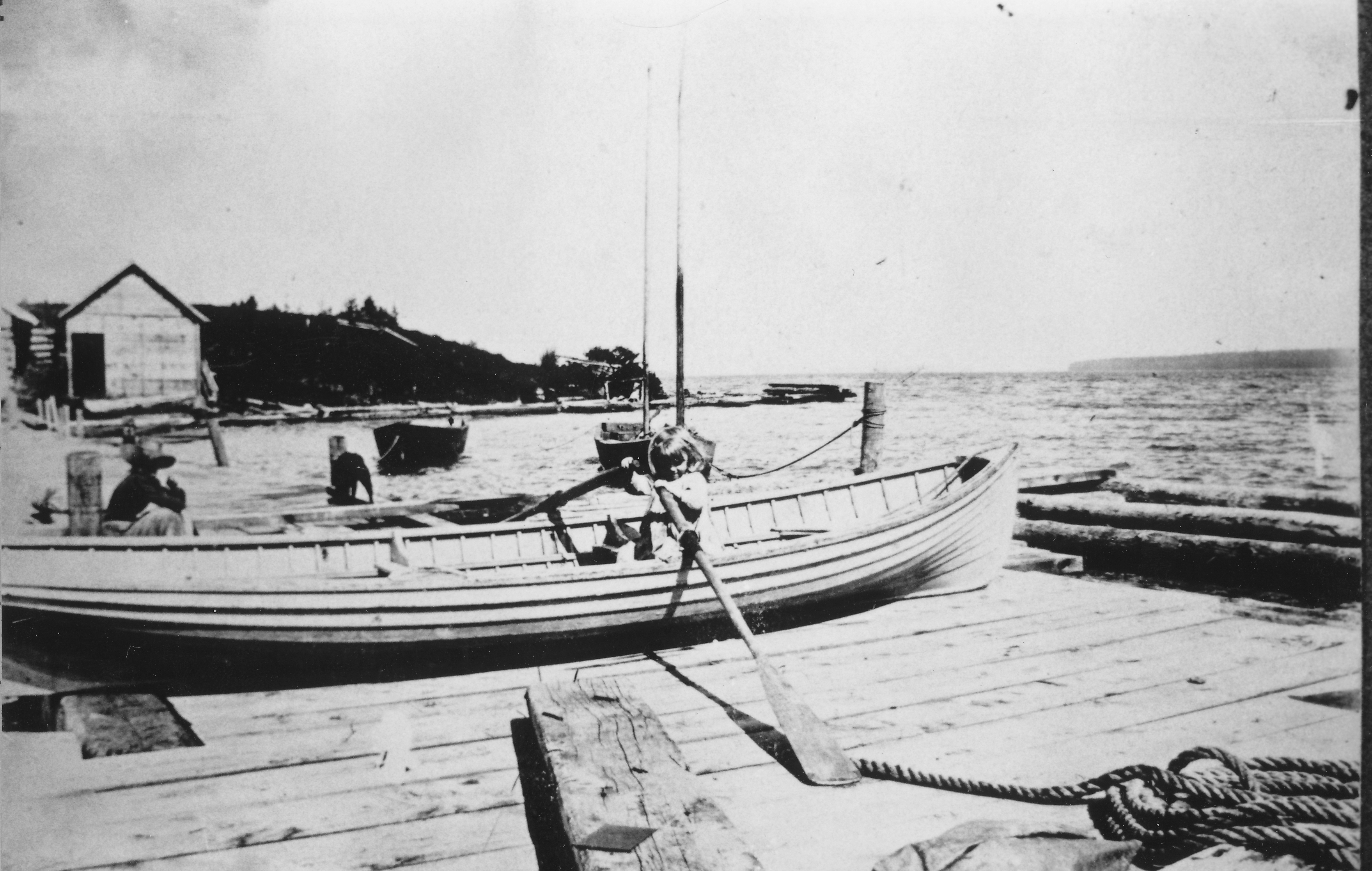 A black and white photo of a girl in a Mackinaw boat.