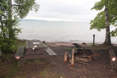 Forested camping area with a view of the lake.