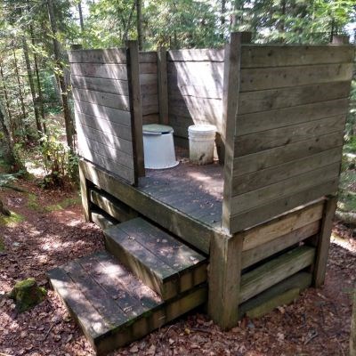 Back country compost toilet surrounded by wood paneling.