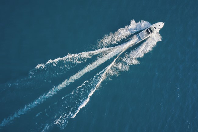 Photograph of a motorboat travelling across blue water viewed from above.