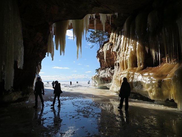 The silhouette of three people standing inside ice caves on the frozen lake.