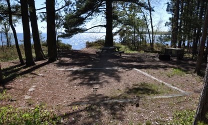 Tent pad, bear locker, picnic table, and fire ring, overlooking Lake Superior on a sunny day.