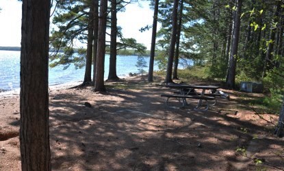 Tent pad, bear locker, and picnic table at campsite nineteen on Stockton Island, next to the beach on Lake Superior.
