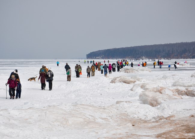 Photograph of people walking on lake ice.
