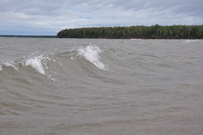 3 foot waves on lake near tree lined shore.
