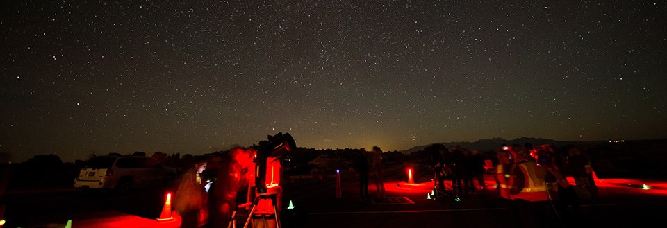 people illuminated by red lights with a starry sky overhead