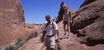 A pair of hikers walk along a smooth rock surface