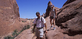 A pair of hikers walking on a large smooth rock