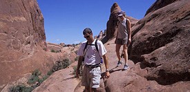 A pair of hikers walking on a large smooth rock