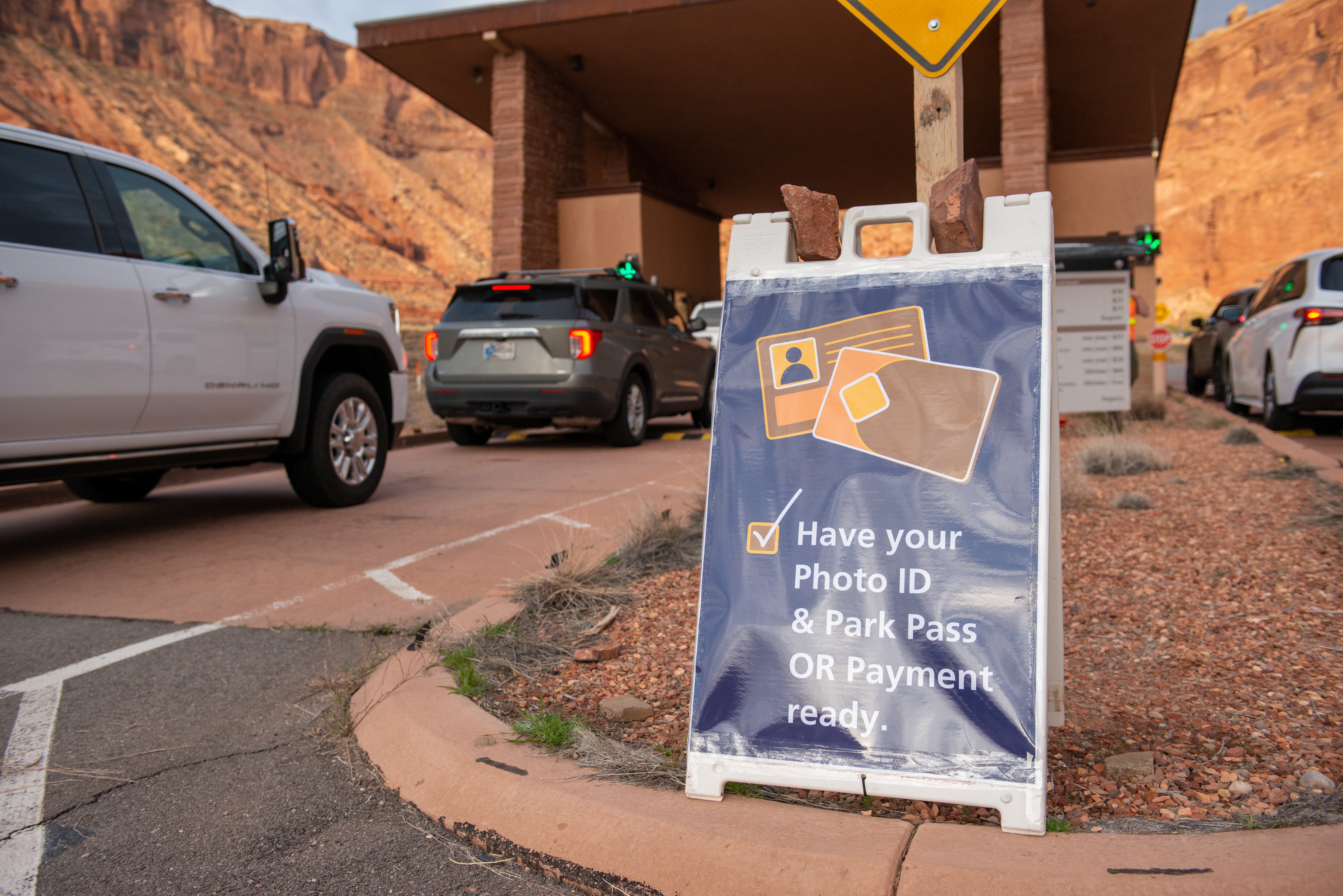 cars approach an entrance booth, passing a sign reading Have your photo ID and park pass or payment ready cars approach an entrance booth, passing a sign reading Have your photo ID and park pass or payment ready